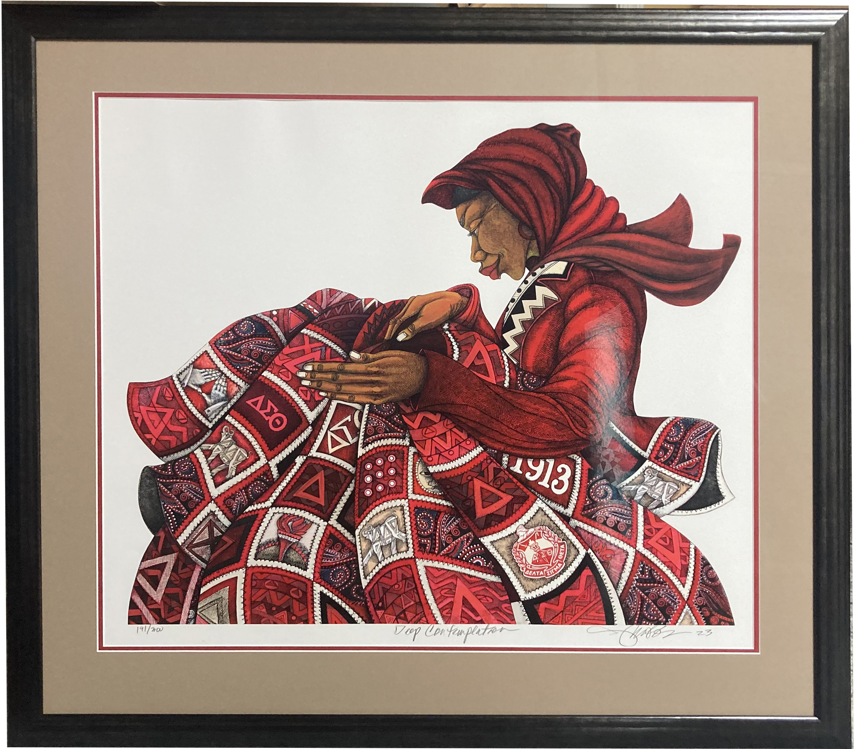 Framed Charles Bibbs print of an african-american lady sitting sewing a quilt in red, white and black
